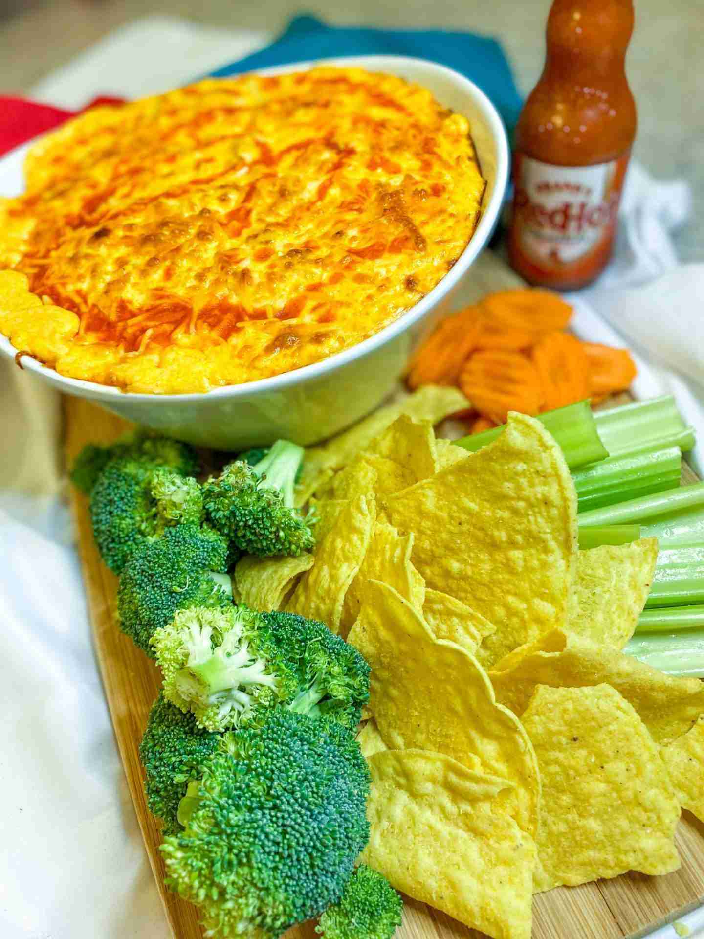Buffalo Chicken Dip in a board with a cutting board covered in finger foods