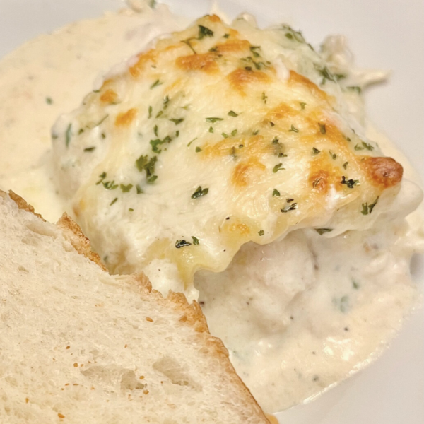 Chicken Alfredo Lasagan Rolls on a white plate with a piece of french bread