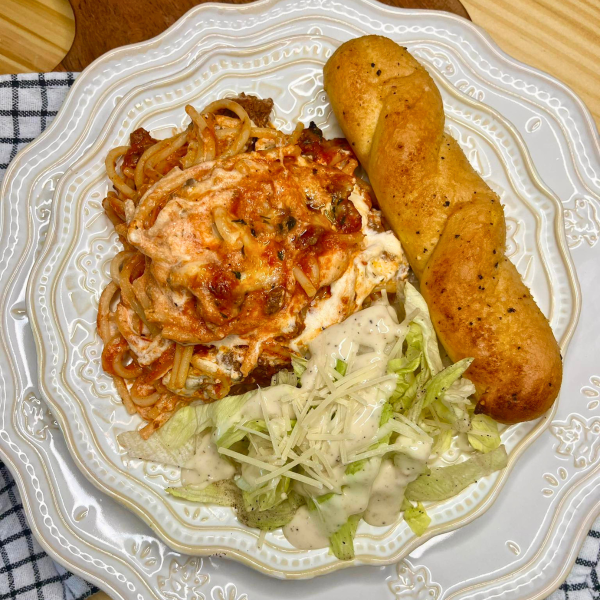 Overhead image of Million Dollar Spaghetti on a plate with salad and a breadstick