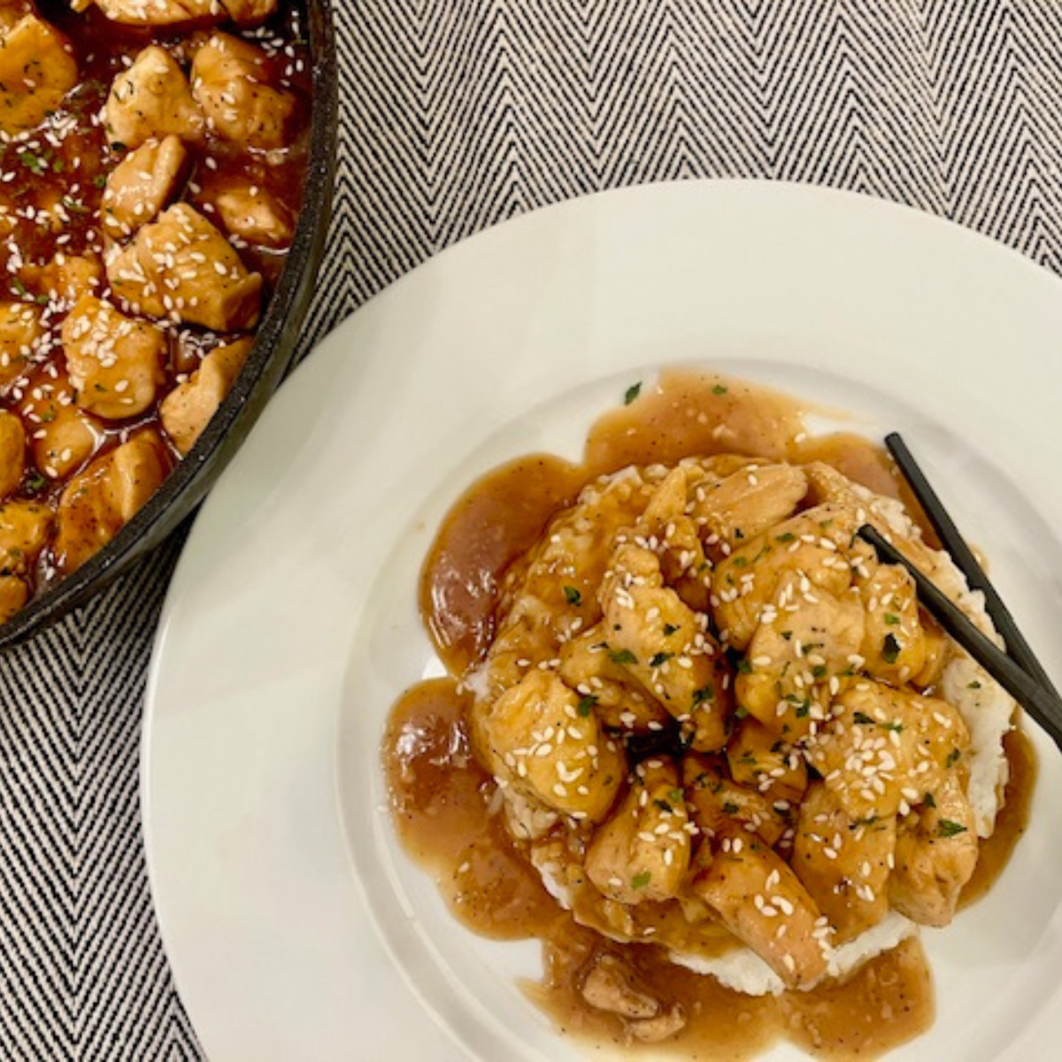 Overhead image of a plate of Bourbon Chicken with a skillet next to it