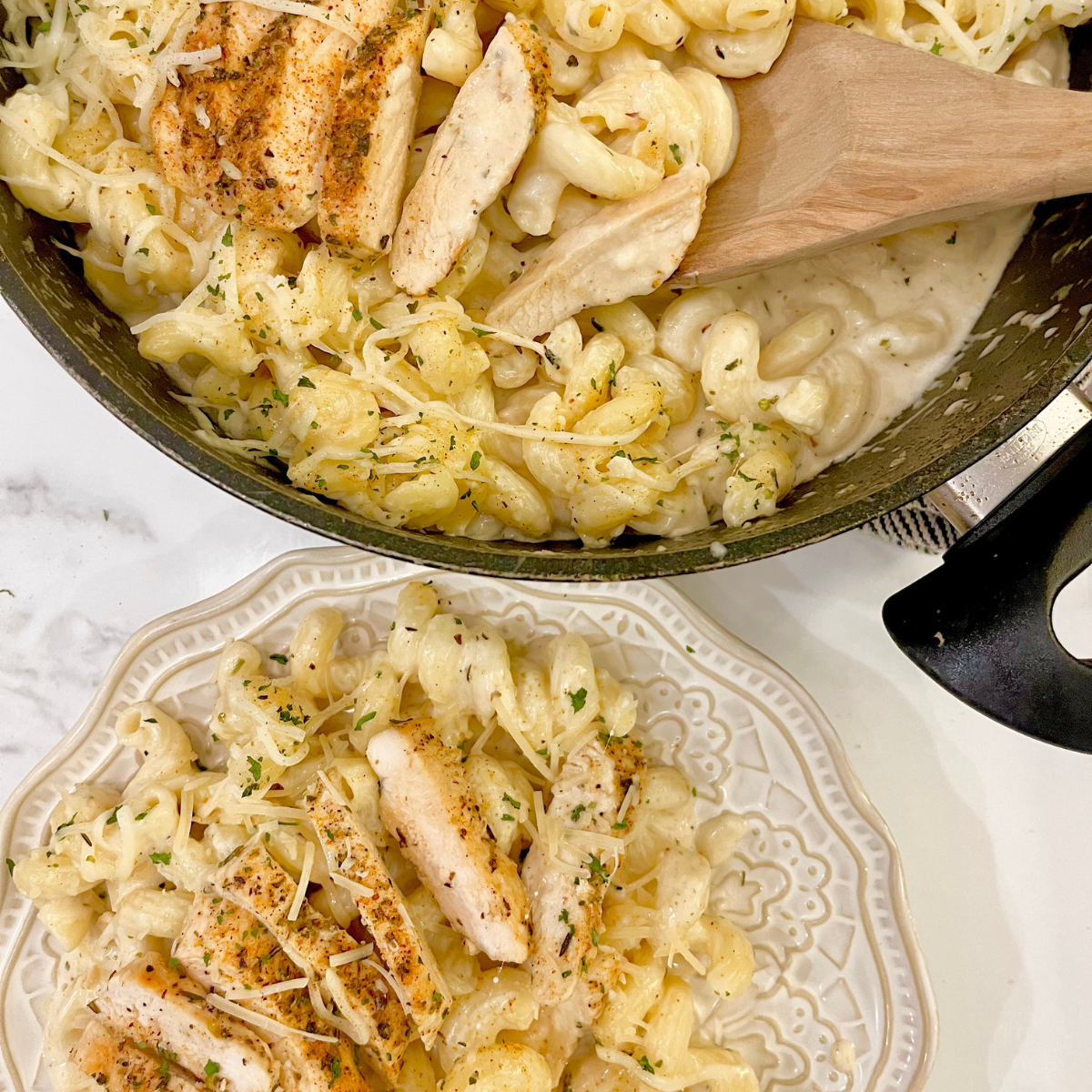 Cajun Chicken Alfredo on a decorative plate with a pan full of it nearby