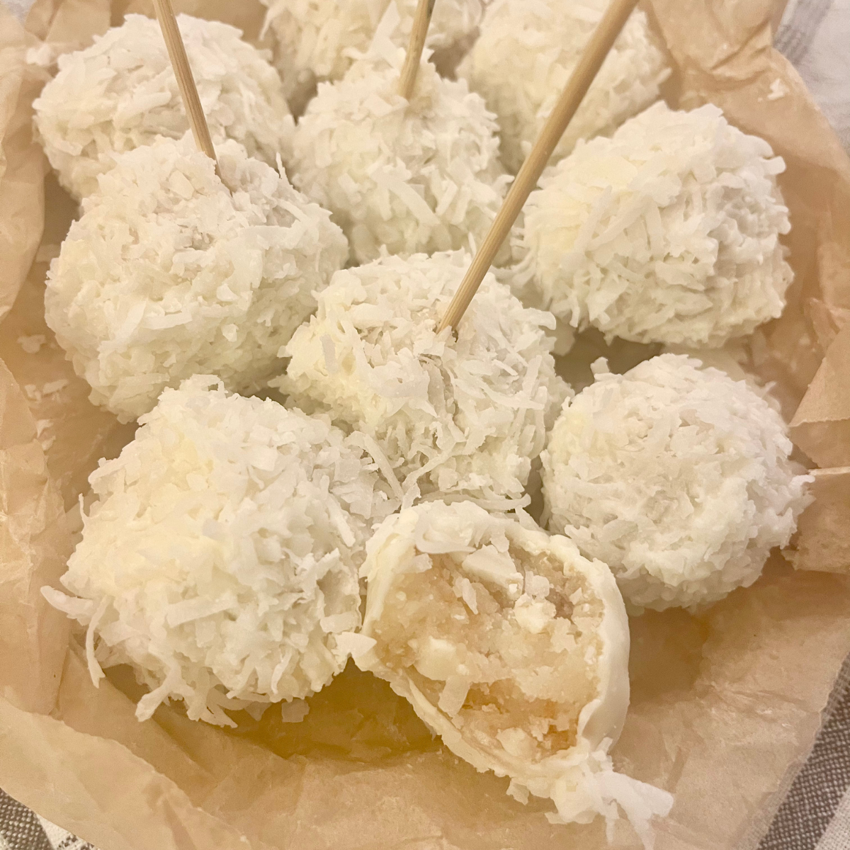 Coconut Cake Balls assembled and stacked on crumpled parchment paper