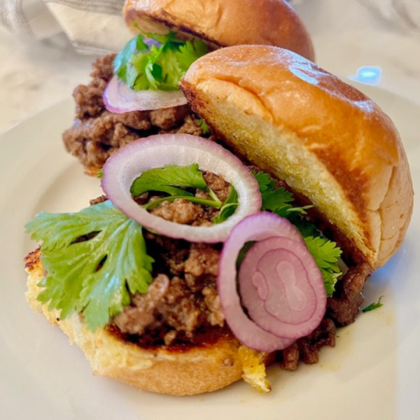 Close up image of two lamb sliders on a white plate