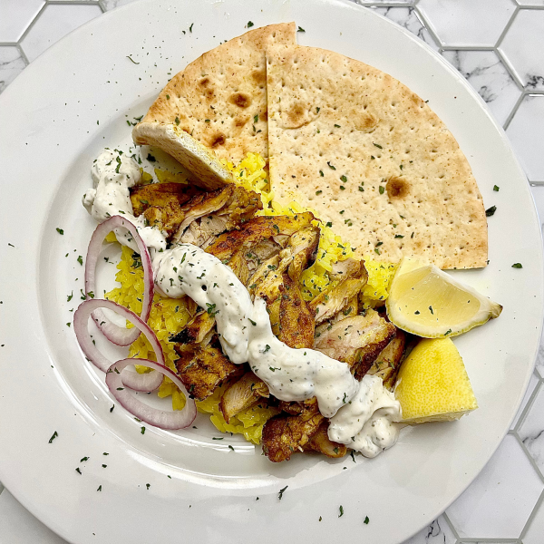 Baked Chicken Shawarma on a white plate with rice, pita, and tzatziki