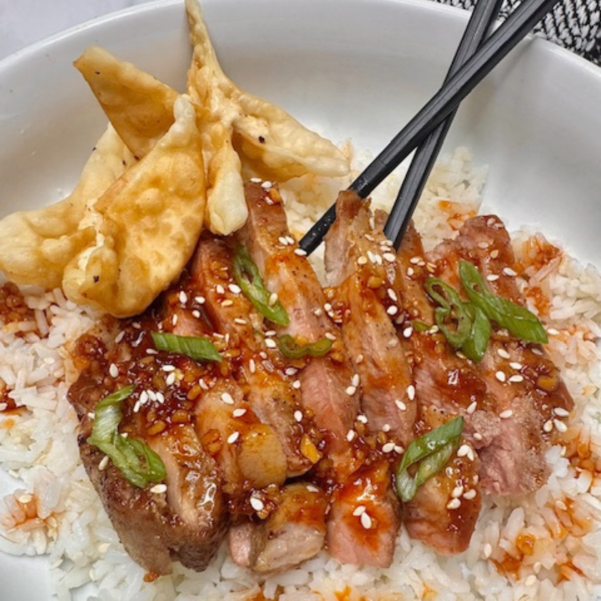 Sliced air fryer pork steak with Korean bbq sauce over rice