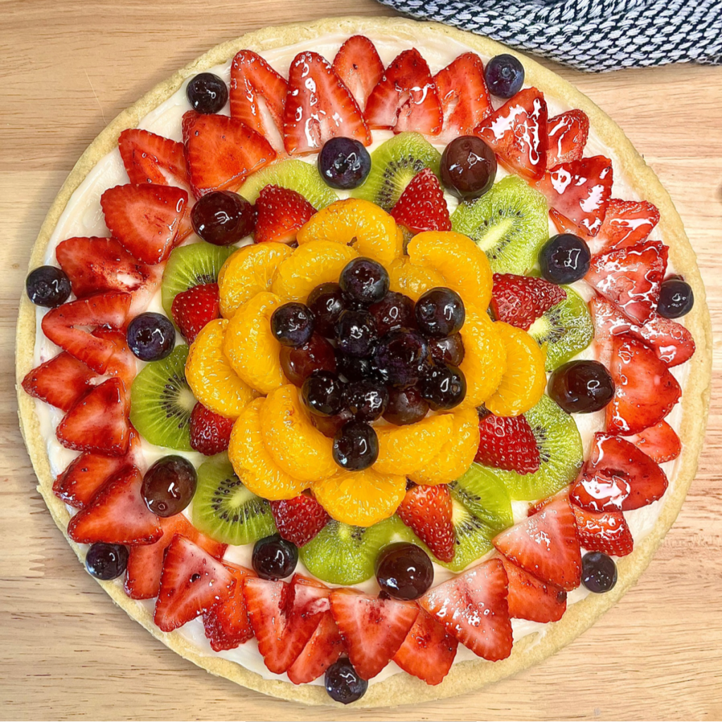 Overhead image of fruit arranged over the top of the sugar cookie crust and sweetened cream cheese frosting