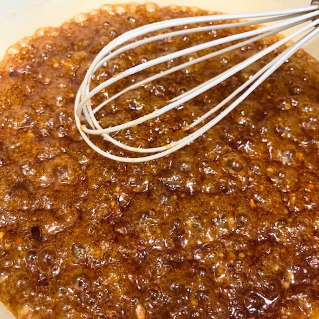 Homemade Sweet Chili Chicken Sauce in a skillet with a whisk