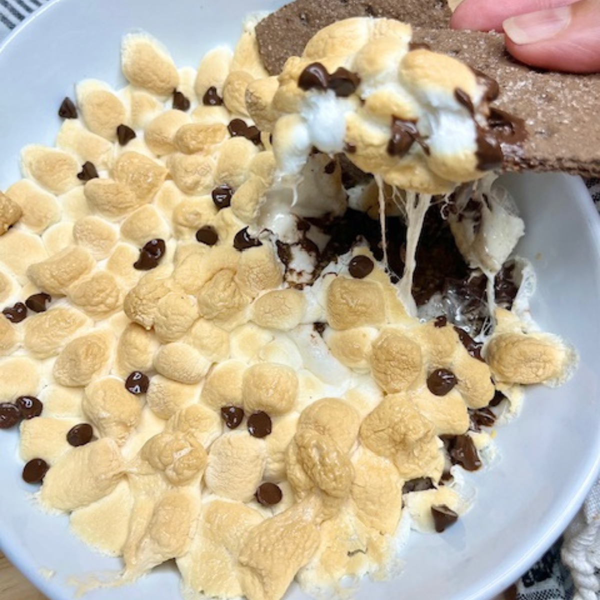 Air Fryer S'mores Dip being scooped with chocolate graham crackers