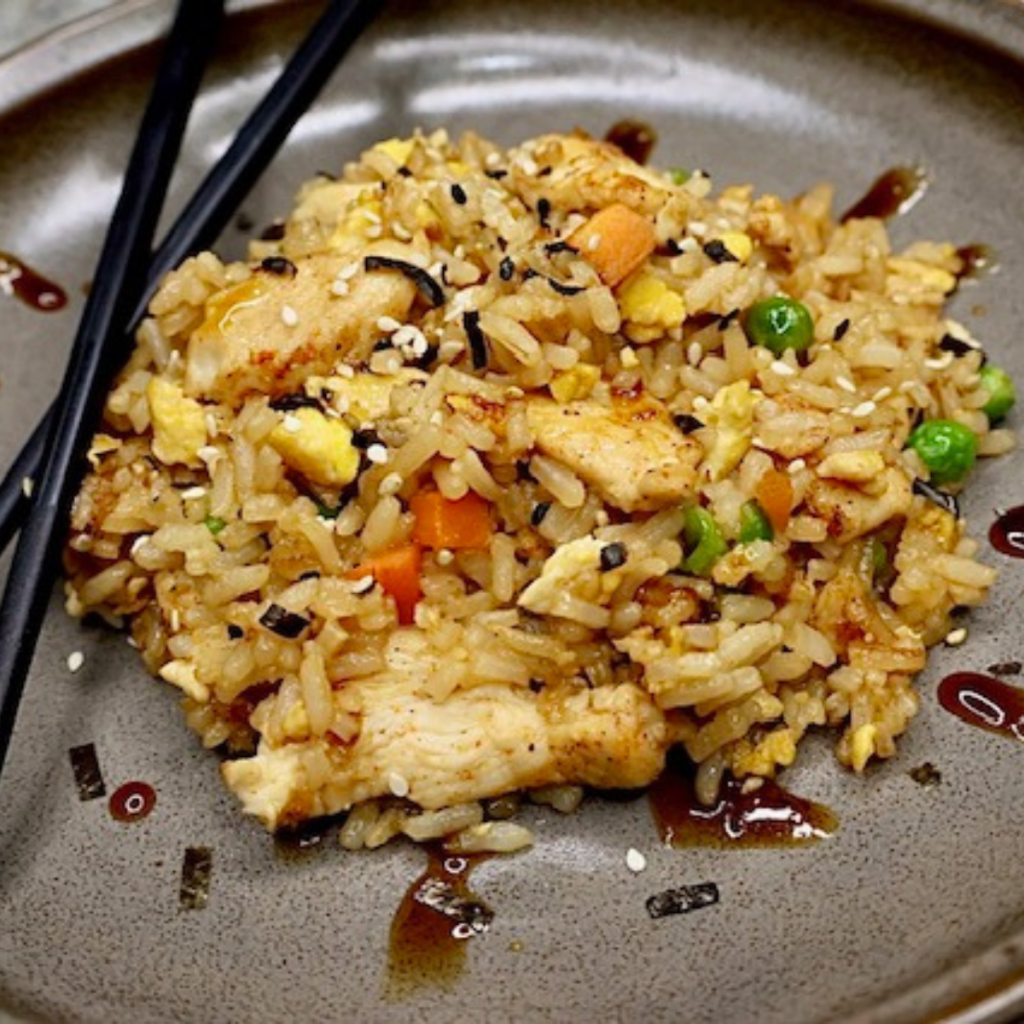 Close up image of homemade chicken fried rice on a plate with chopsticks