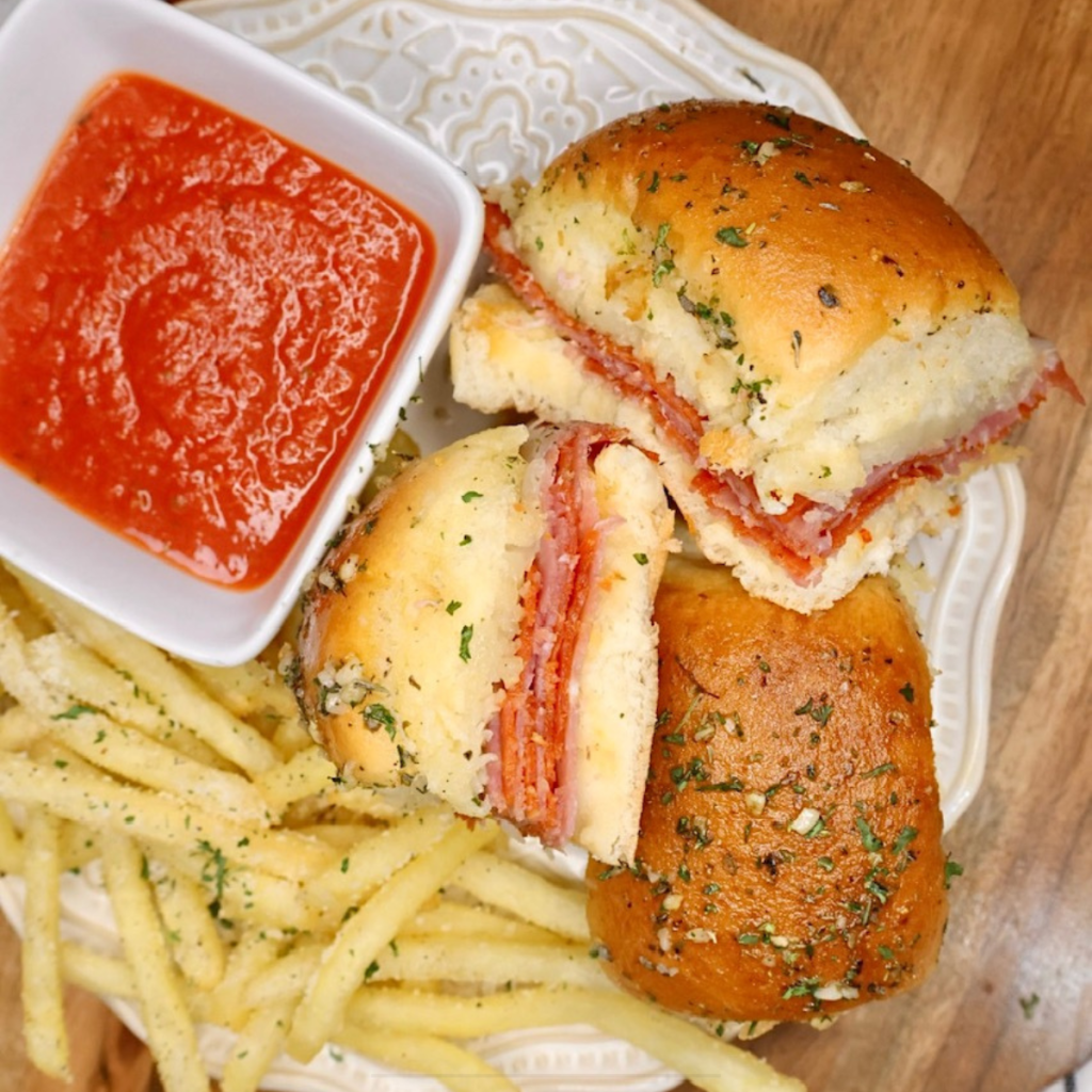 Three Hawaiian Roll Italian Sliders on a plate with french fries and marinara dipping sauce
