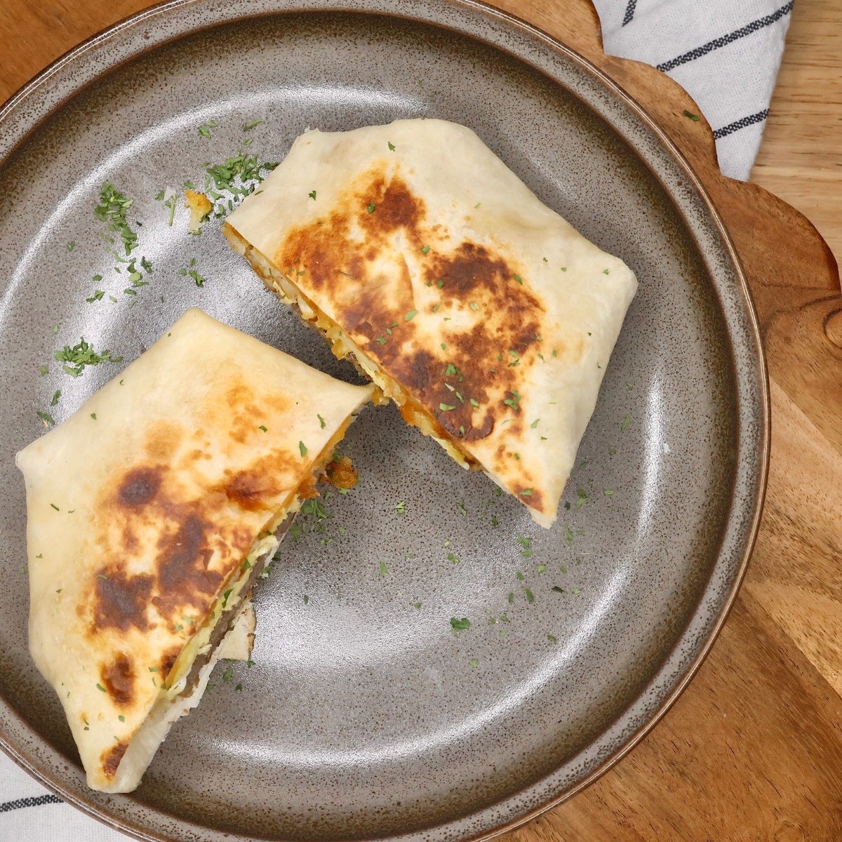 Overhead image of a breakfast crunch wrap cut in half on a plate