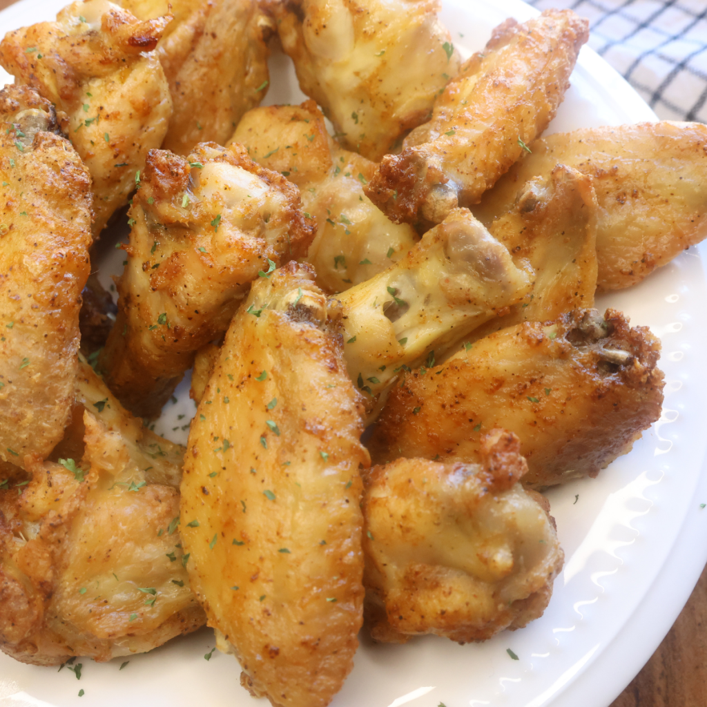 Close up shot of crispy chicken wings on a white plate