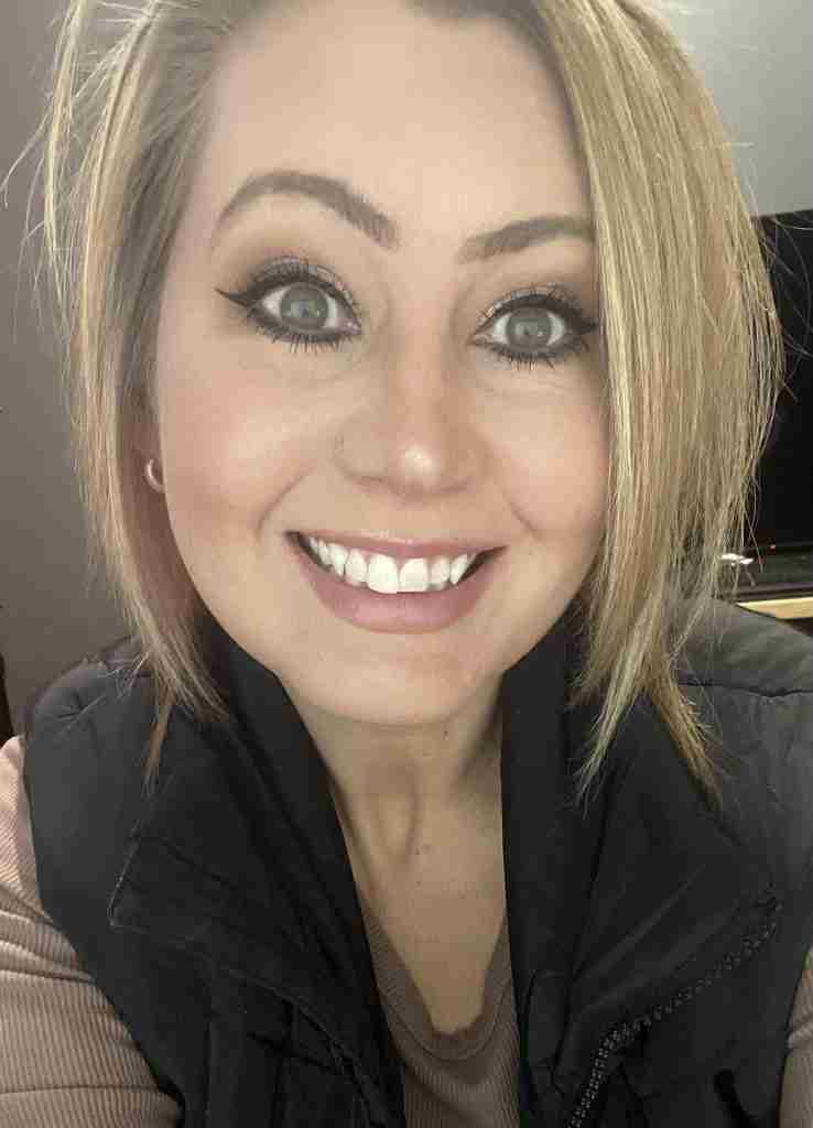 Ashley Thompson (recipe developer and food blogger for ComfortCooks.com) in a brown shirt and black vest smiling