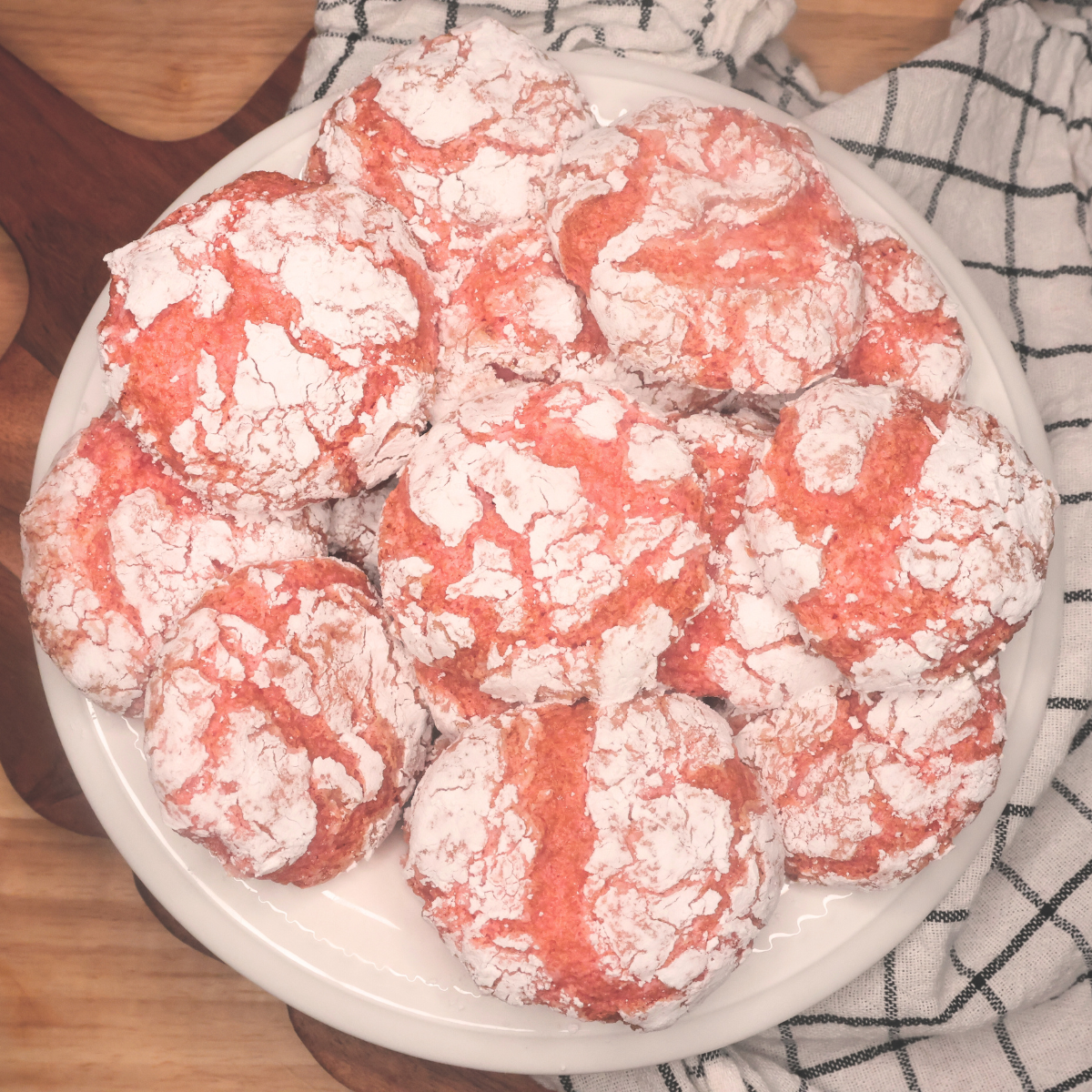 Overhead image of Strawberry Crinkle Cookies on a white dish against a wooden background