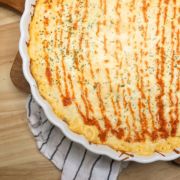 close up image of baked buffalo chicken dip in a white dish