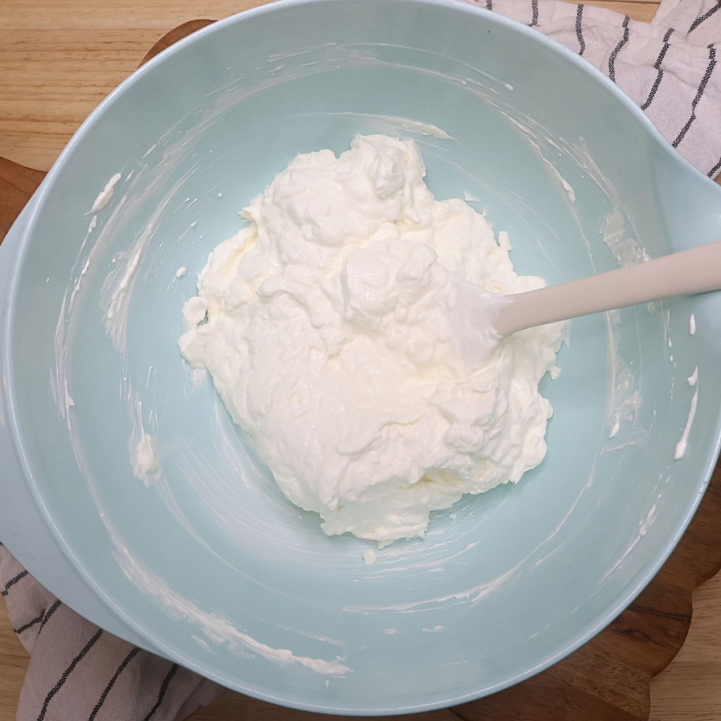 Sour Cream and softened cream cheese mixed together in a blue bowl