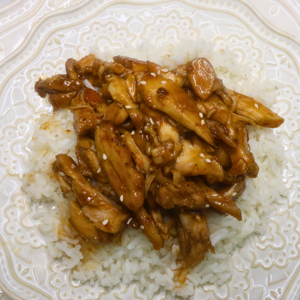 Overhead image of bourbonless chicken thighs over a bed of rice with furikake seasoning garnish