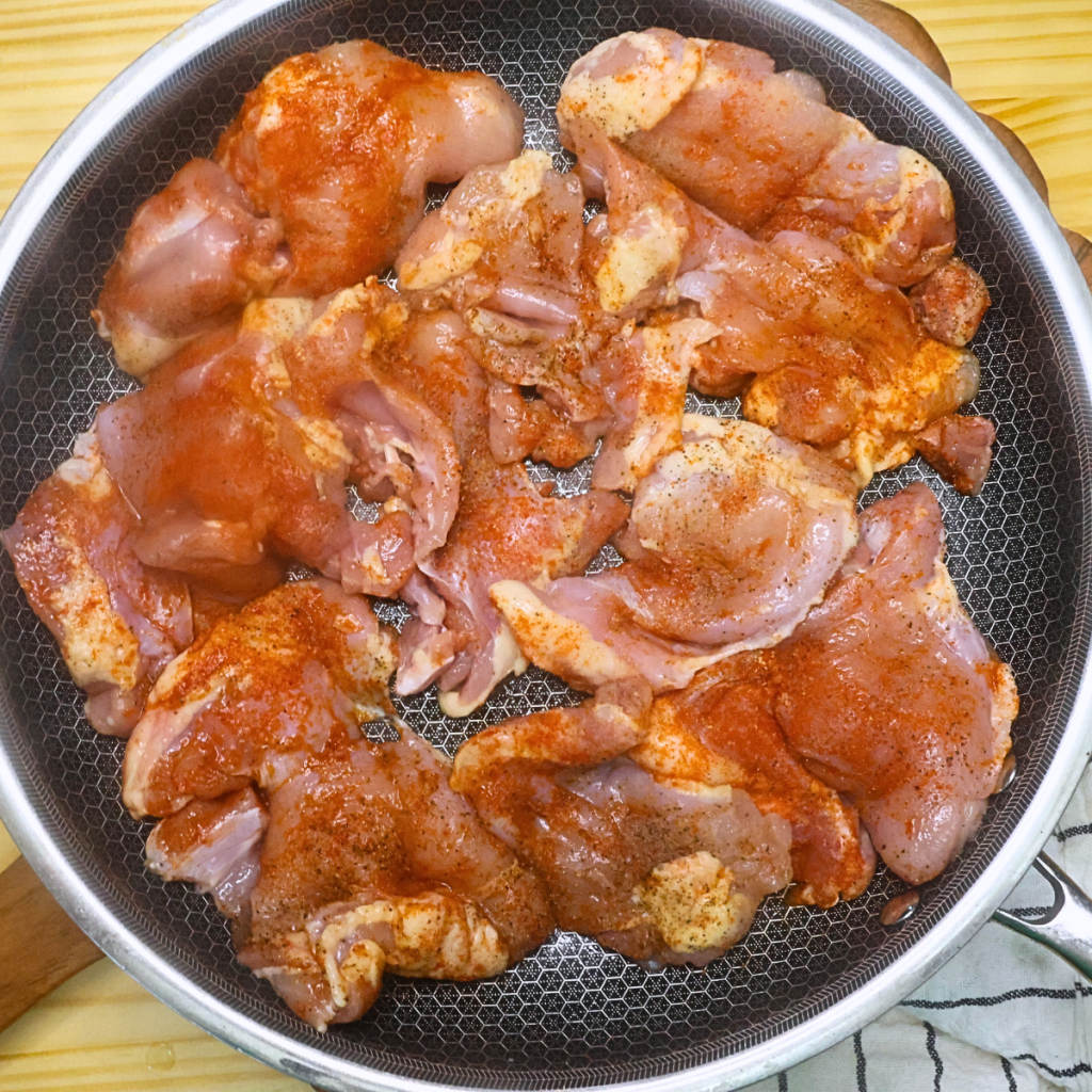 Seasoned boneless chicken thighs in a large skillet