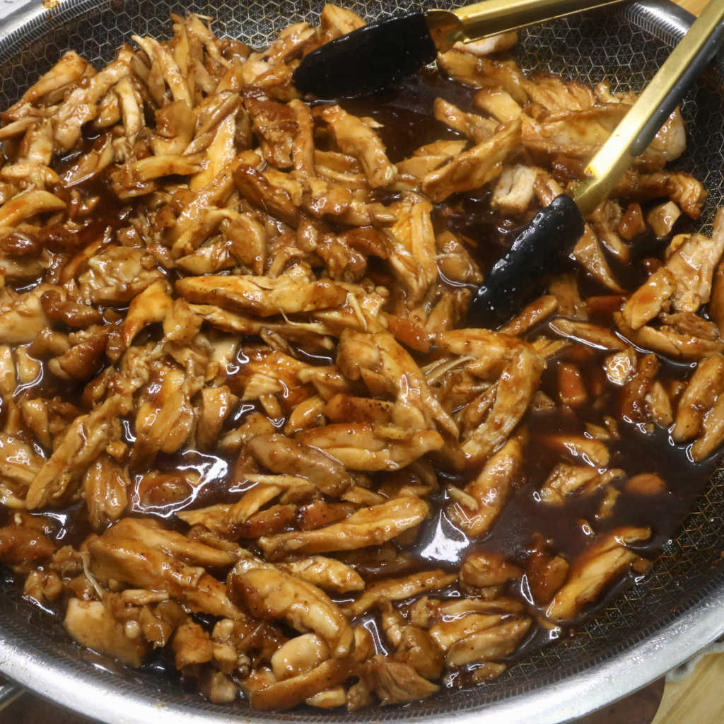 Bourbonless Chicken in a skillet with a pair of tongs