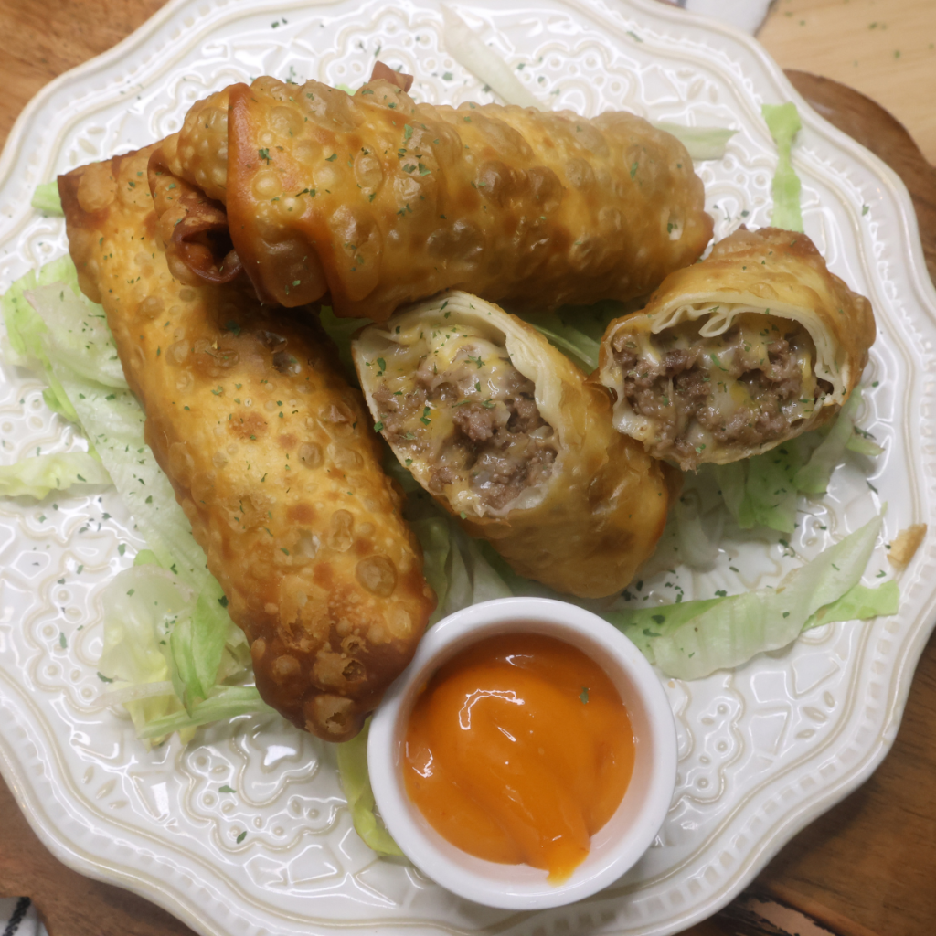 Overhead image of Deep Fried Cheeseburger Egg Rolls on a white plate with lettuce and dipping sauce