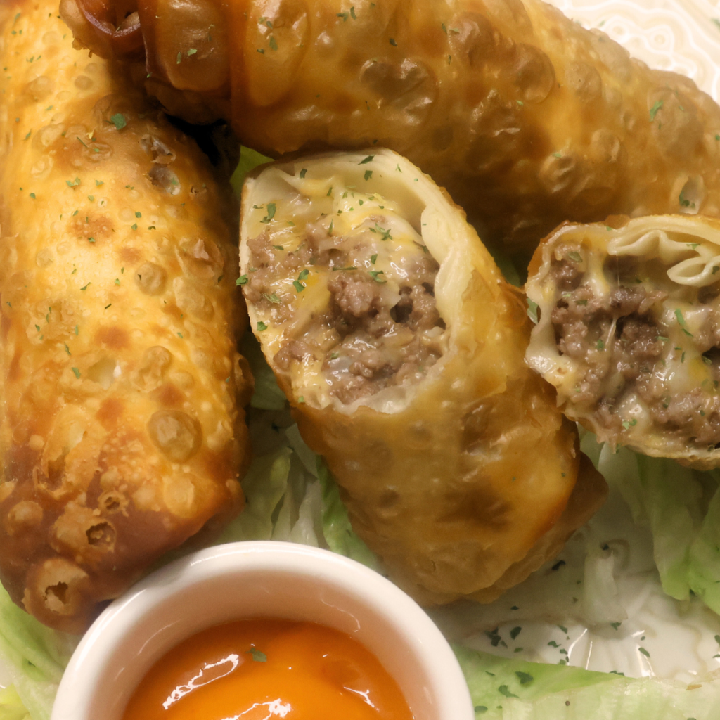Close up image of Cheeseburger egg rolls with one cut in half