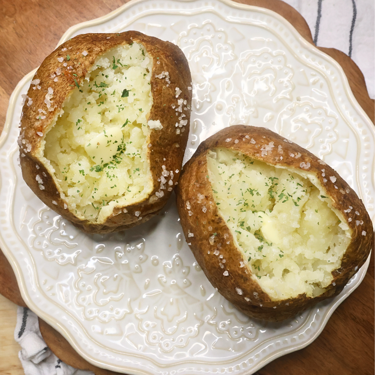 Overhead image of two baked potatoes on a plate with butter