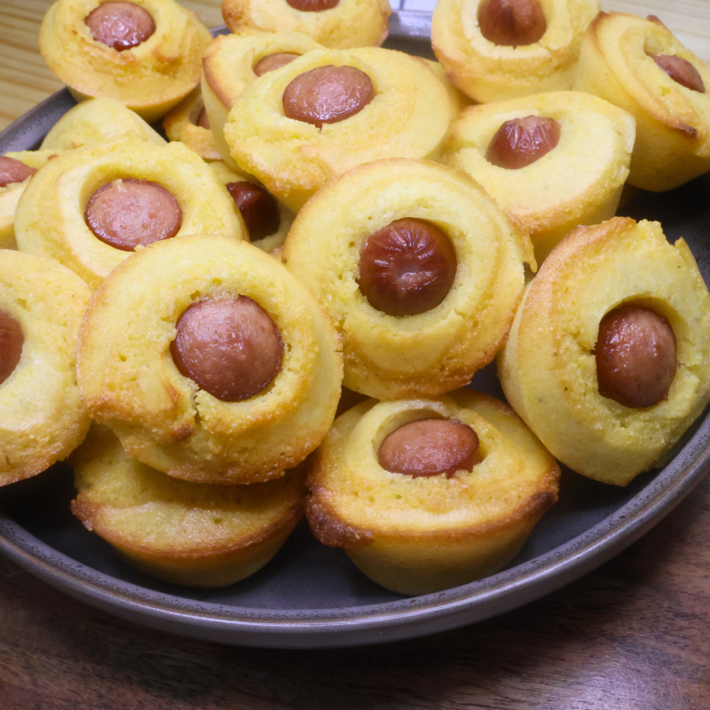 Close up image of mini corn dog muffins piled on a brown plate