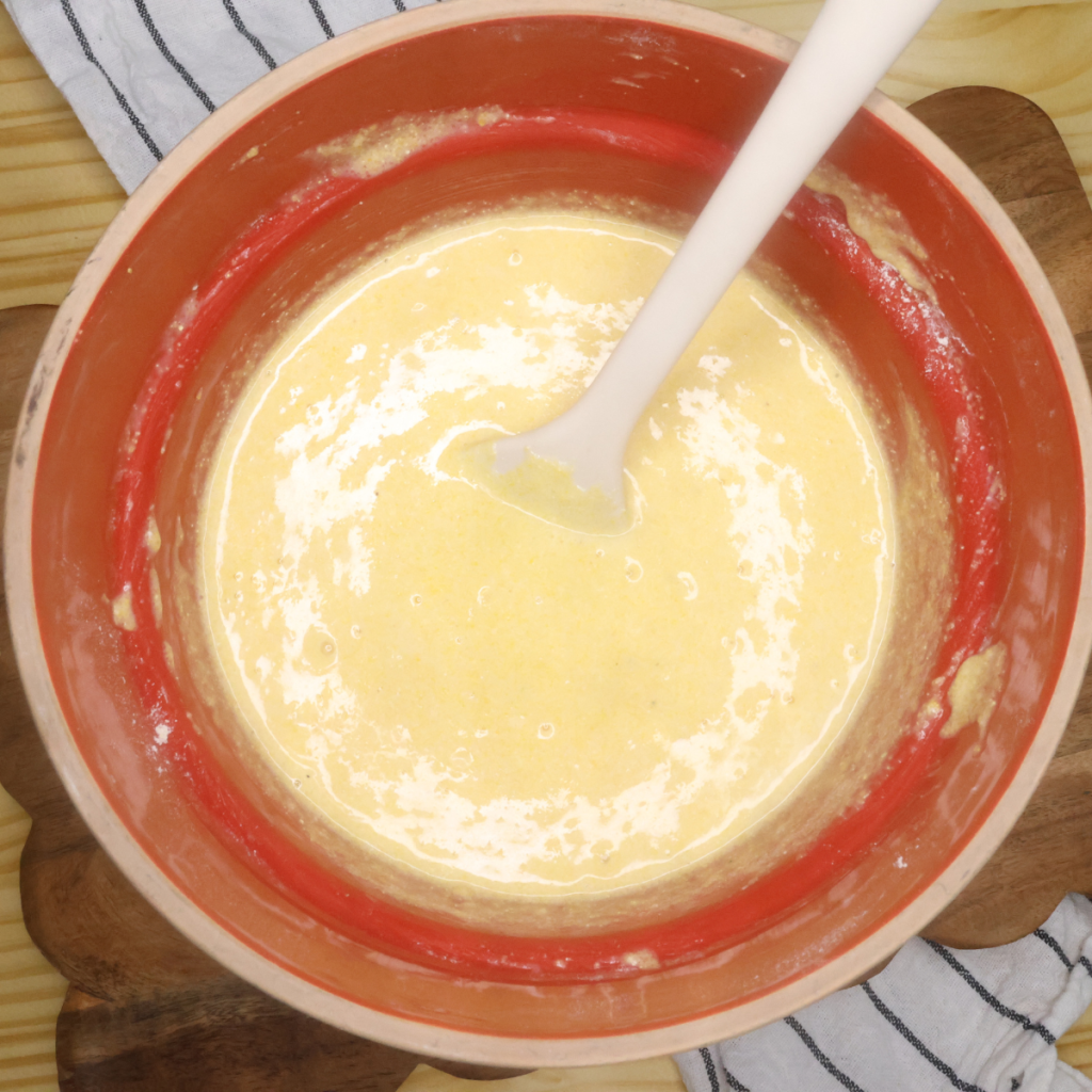 Batter for sweet mini cornbread muffins in a red bowl with a spatula