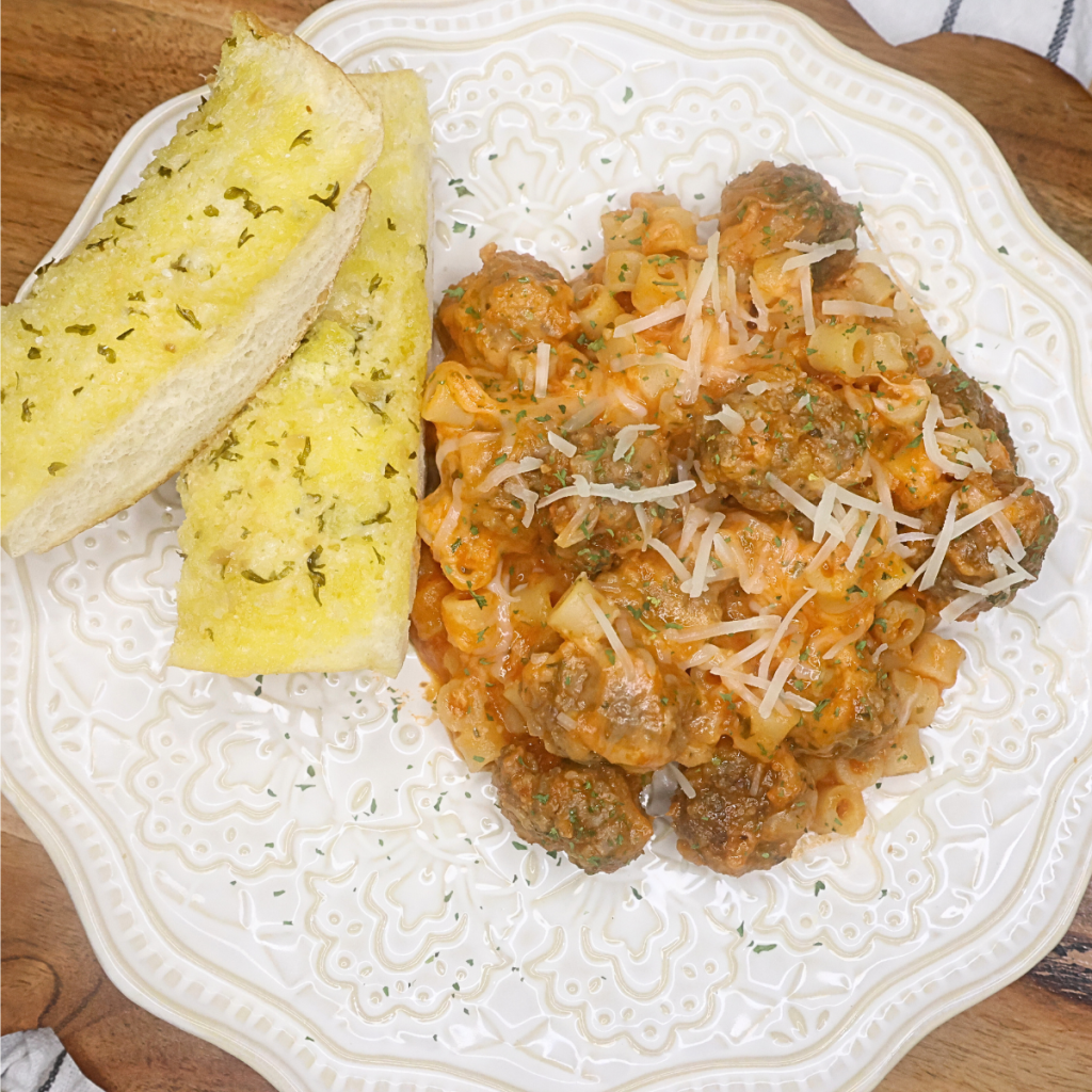 Cheesy ditalini with mini meatballs on a decorative plate with garlic bread