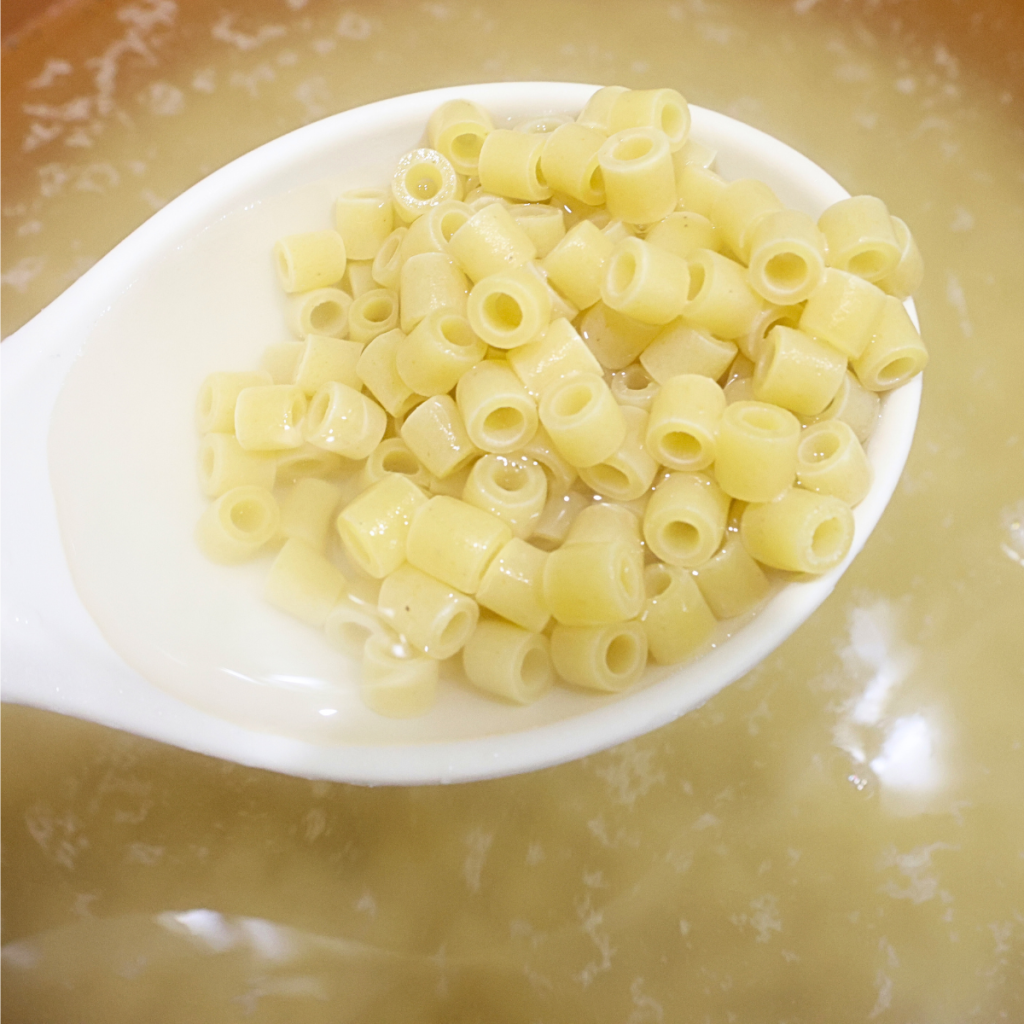 Cooked ditalini on a spoon over a pot of boiling water