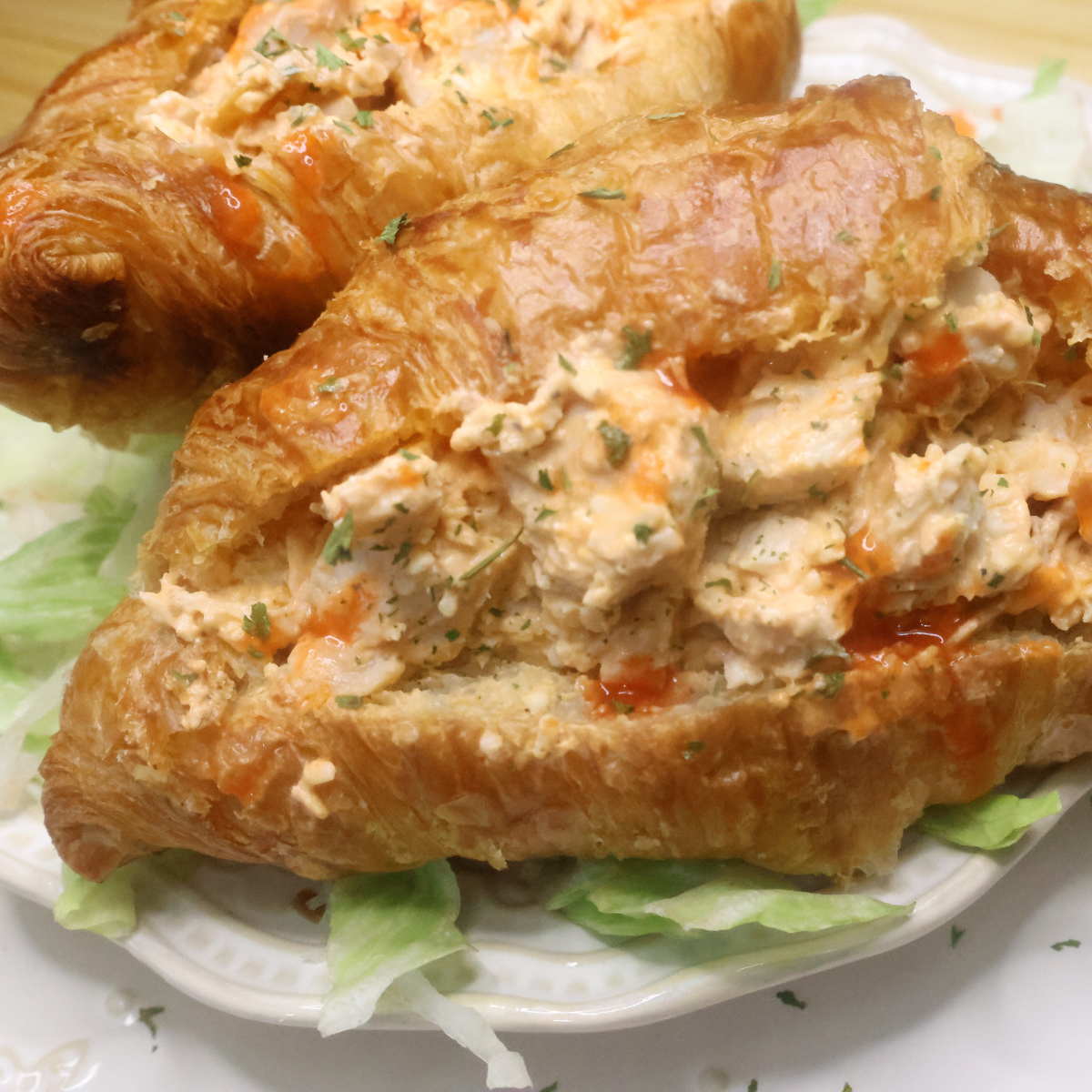 close up image of a buffalo chicken salad sandwich on a croissant