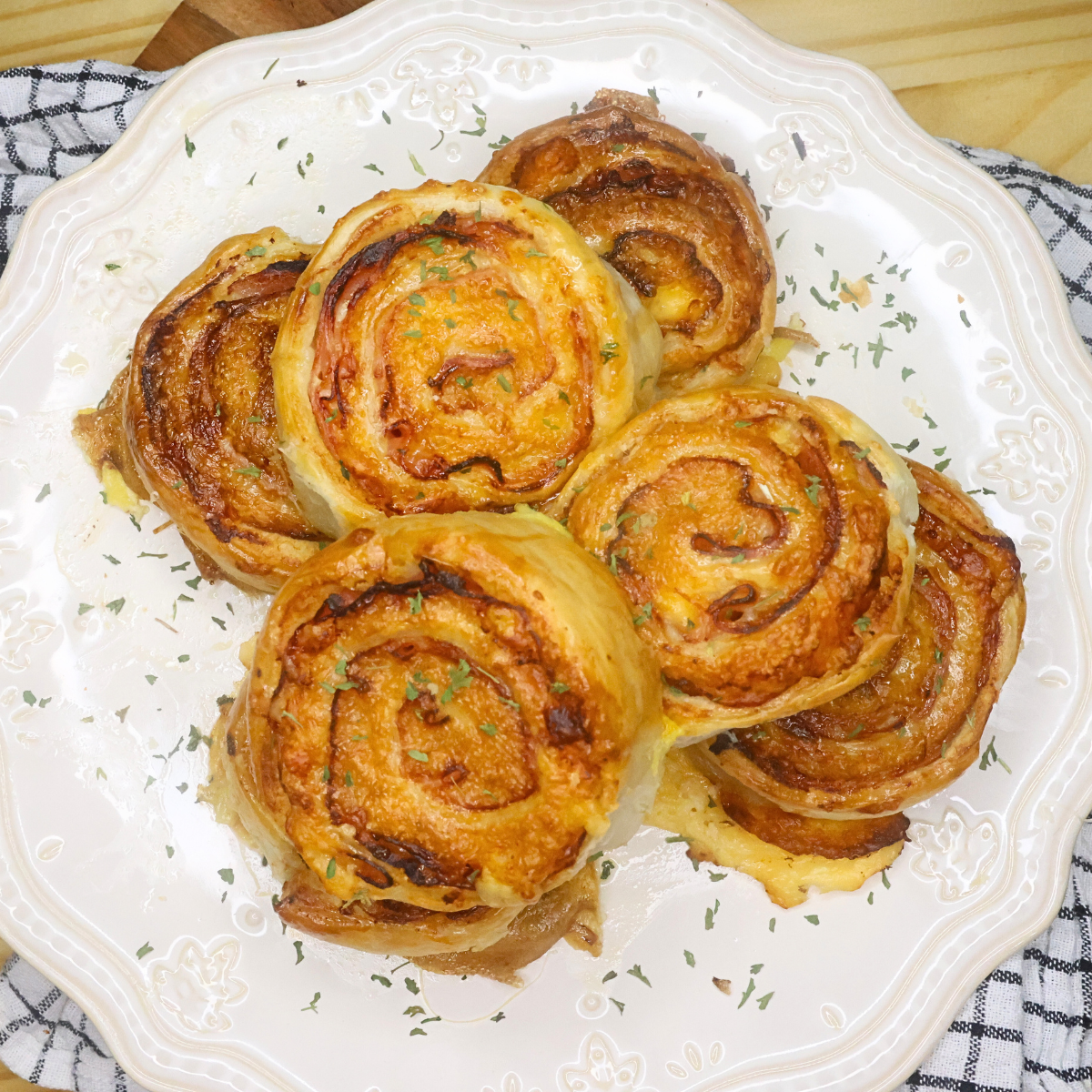 Overhead image of ham and cheese puff pastry pinwheels stacked on a decorative plate