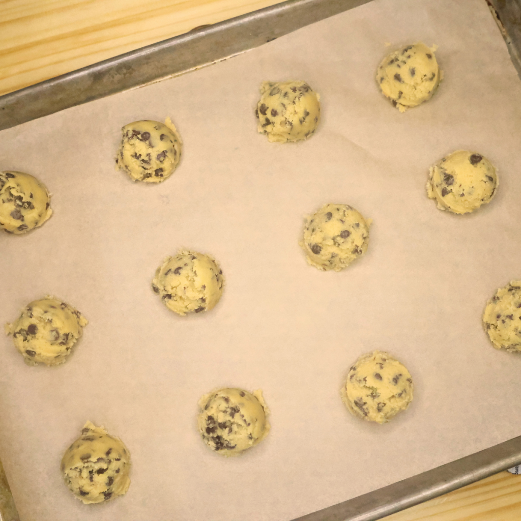 unbaked chocolate chip cookie dough on a pan lined with parchment paper