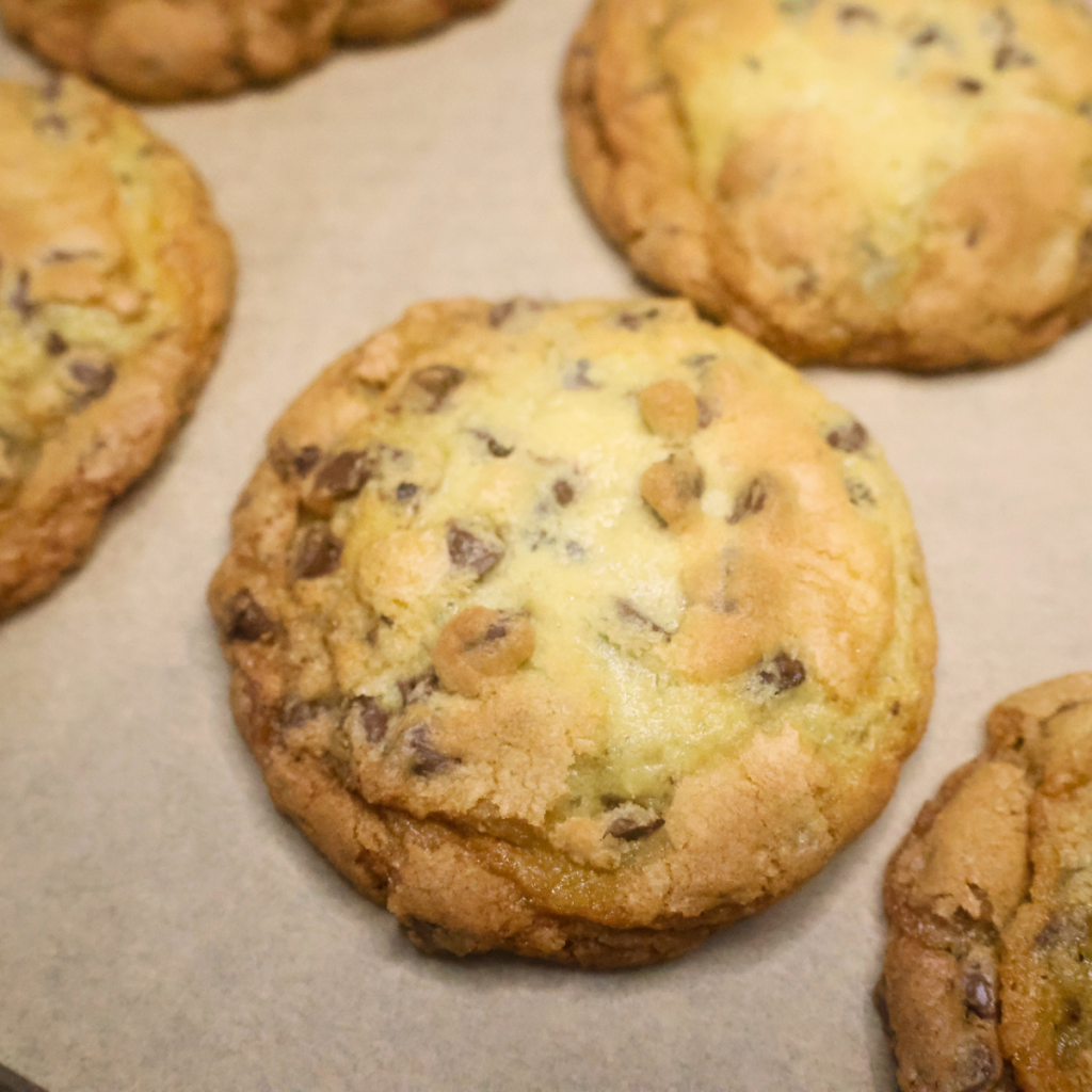 close up image of thin chcoolate chip cookies on parchment paper