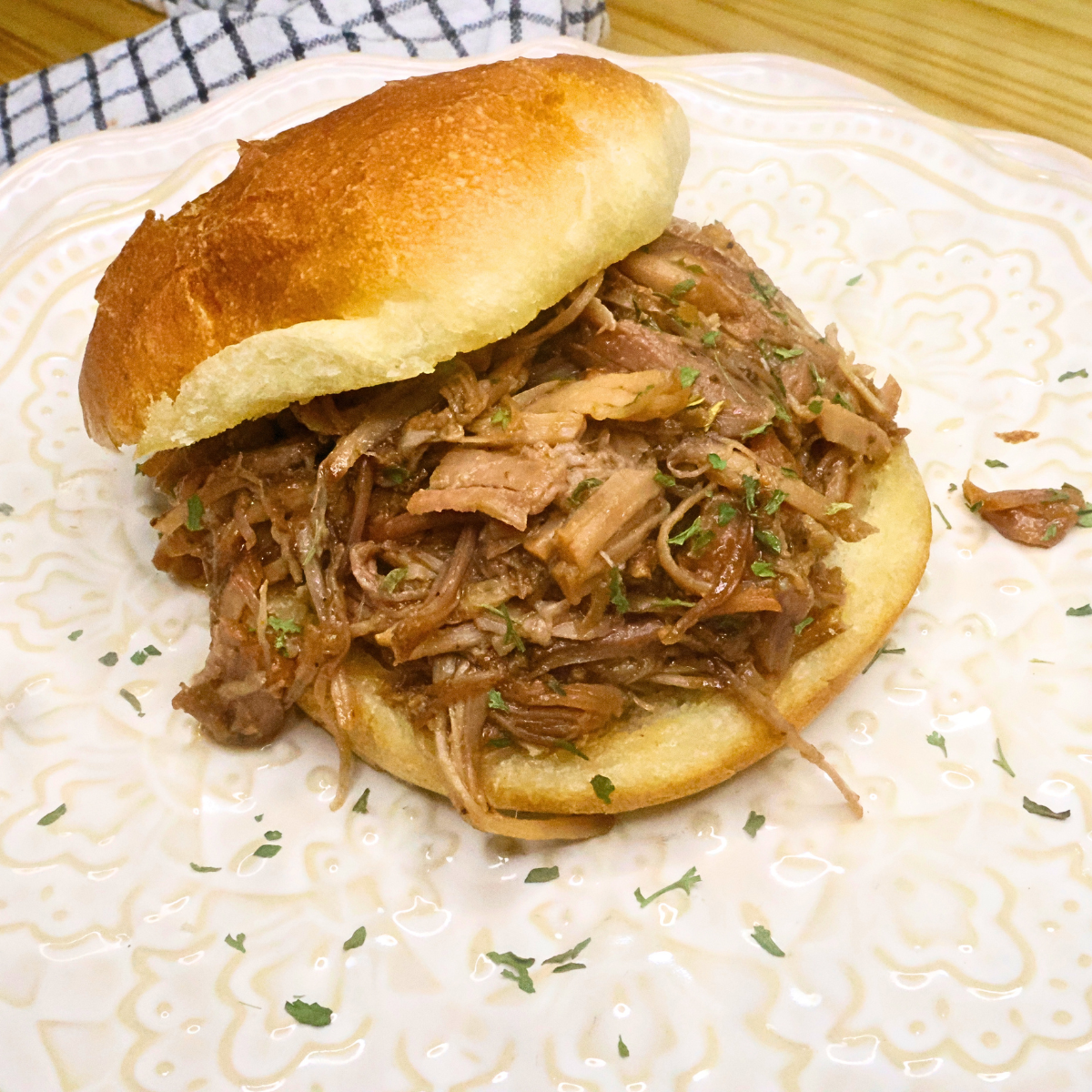 Dr Pepper Pulled Pork on a bun with parsley flakes to garnish