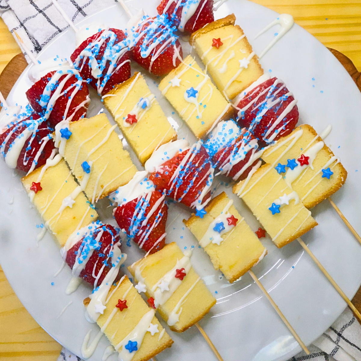 Overhead image of patriotic strawberry shortcake skewers on a white plate