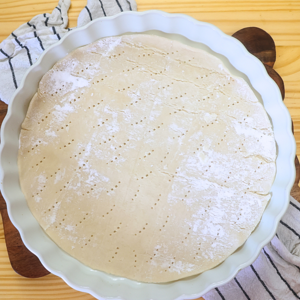refrigerated pie crust rolled out in a pie plate with holes pricked in it