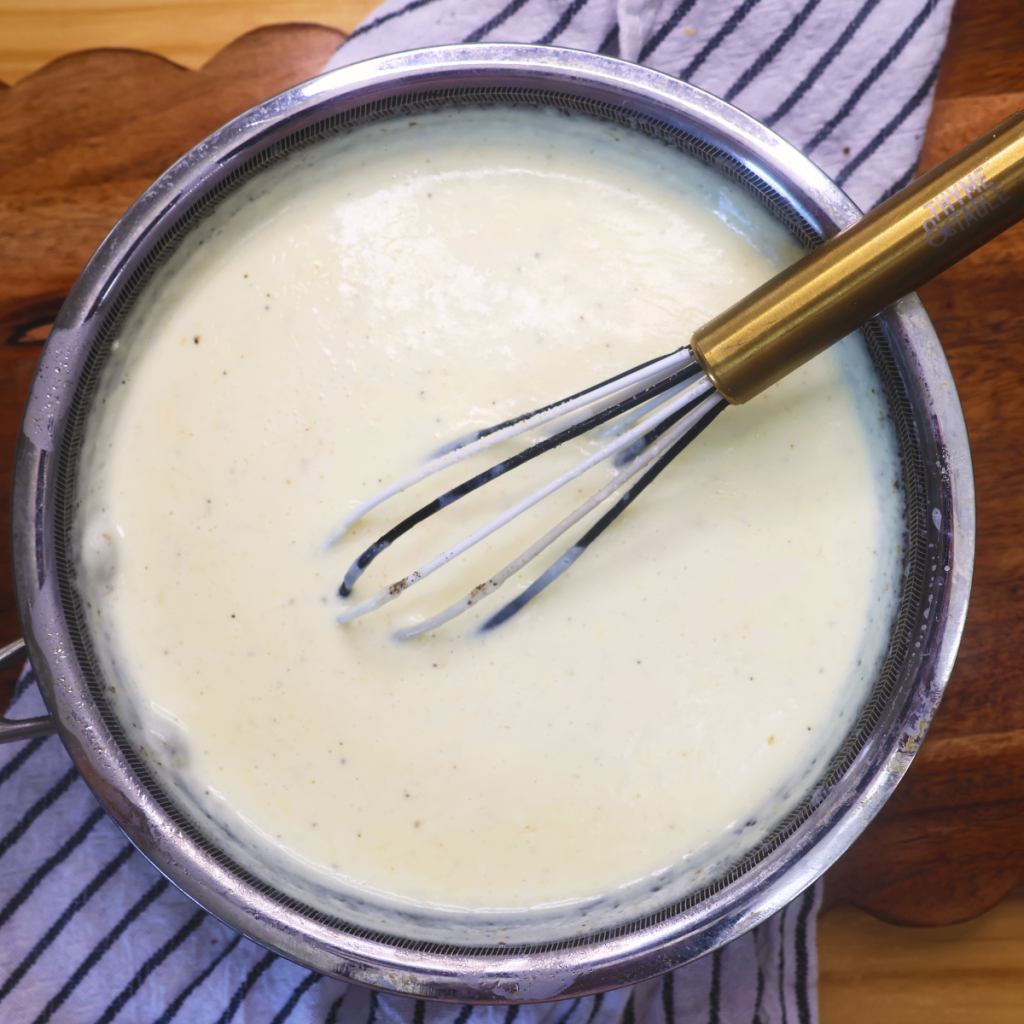 Homemade Alfredo sauce in a pan with a whisk in it