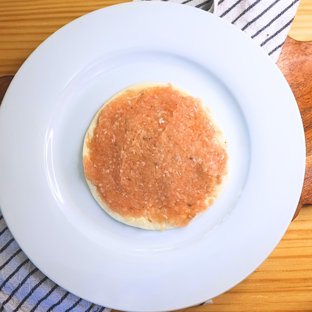 Raw seasoned ground chicken spread over a flour tortilla