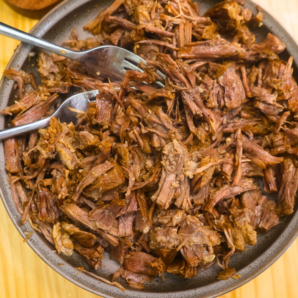 Slow cooker pulled beef on a plate with two forks
